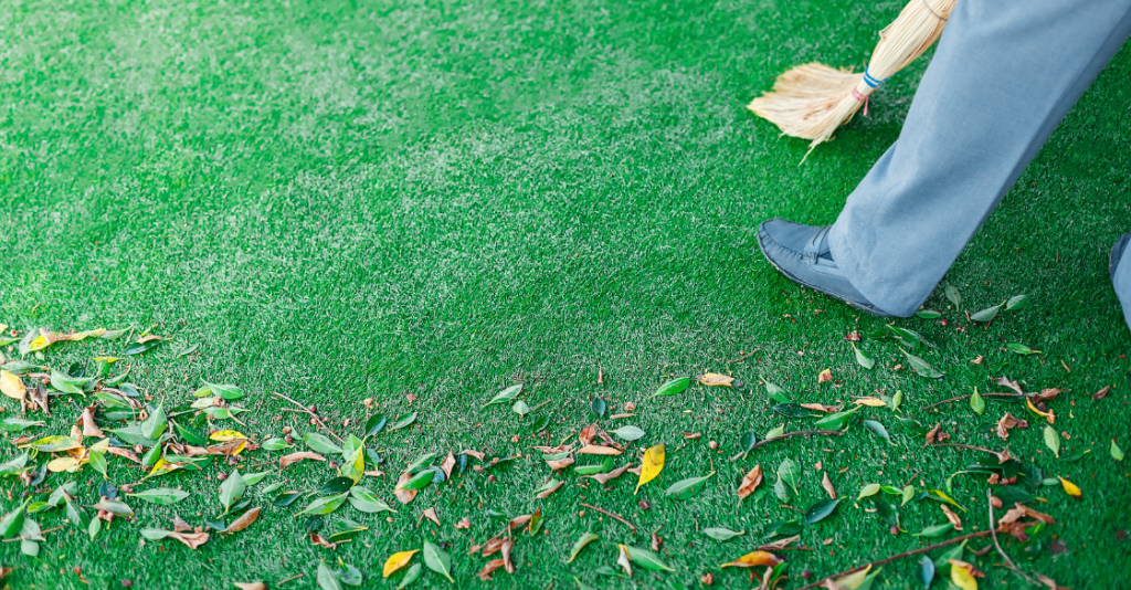 Man sweeps leaves off artificial grass
